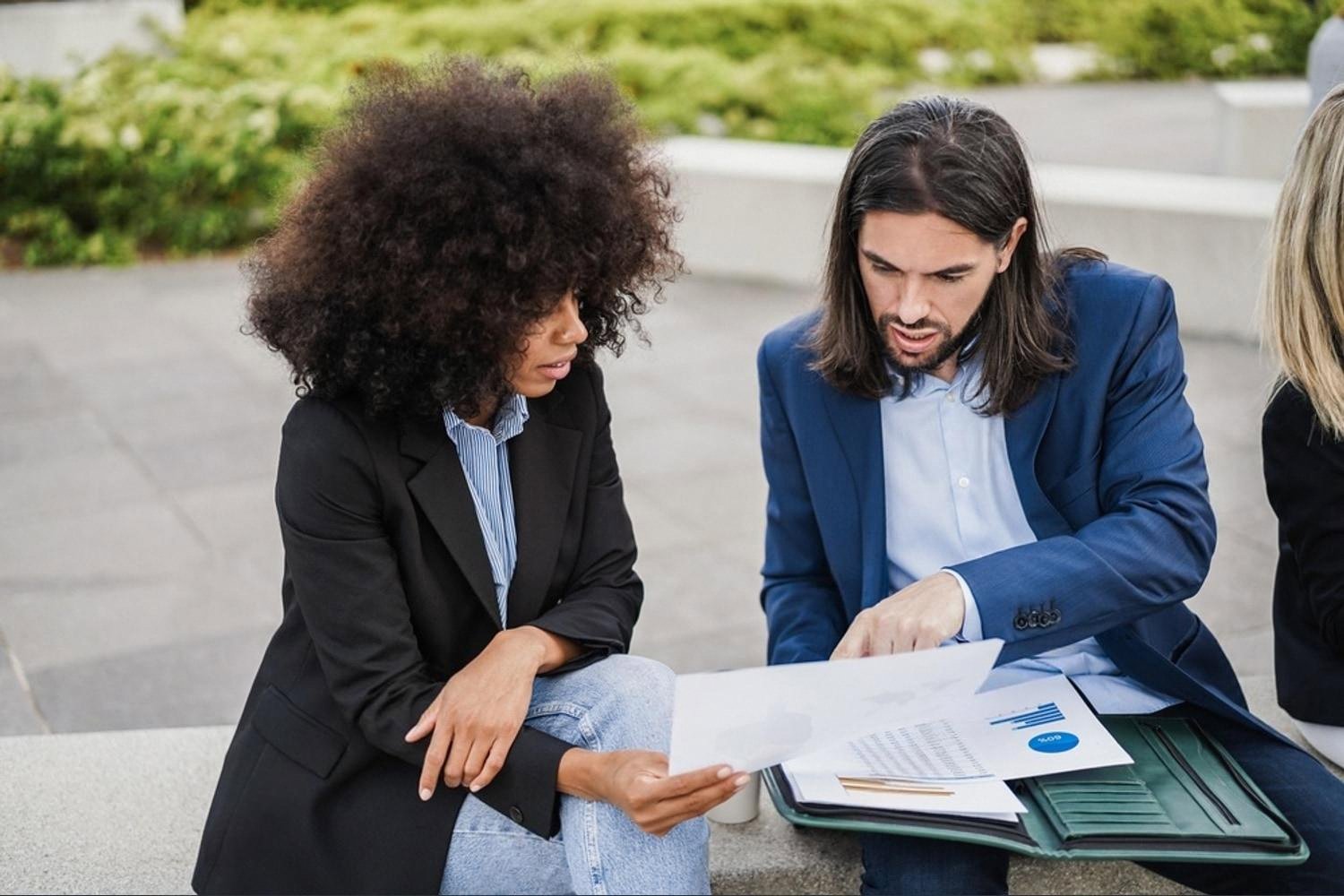 Two finance professionals reviewing reports outdoors in a UAE business district