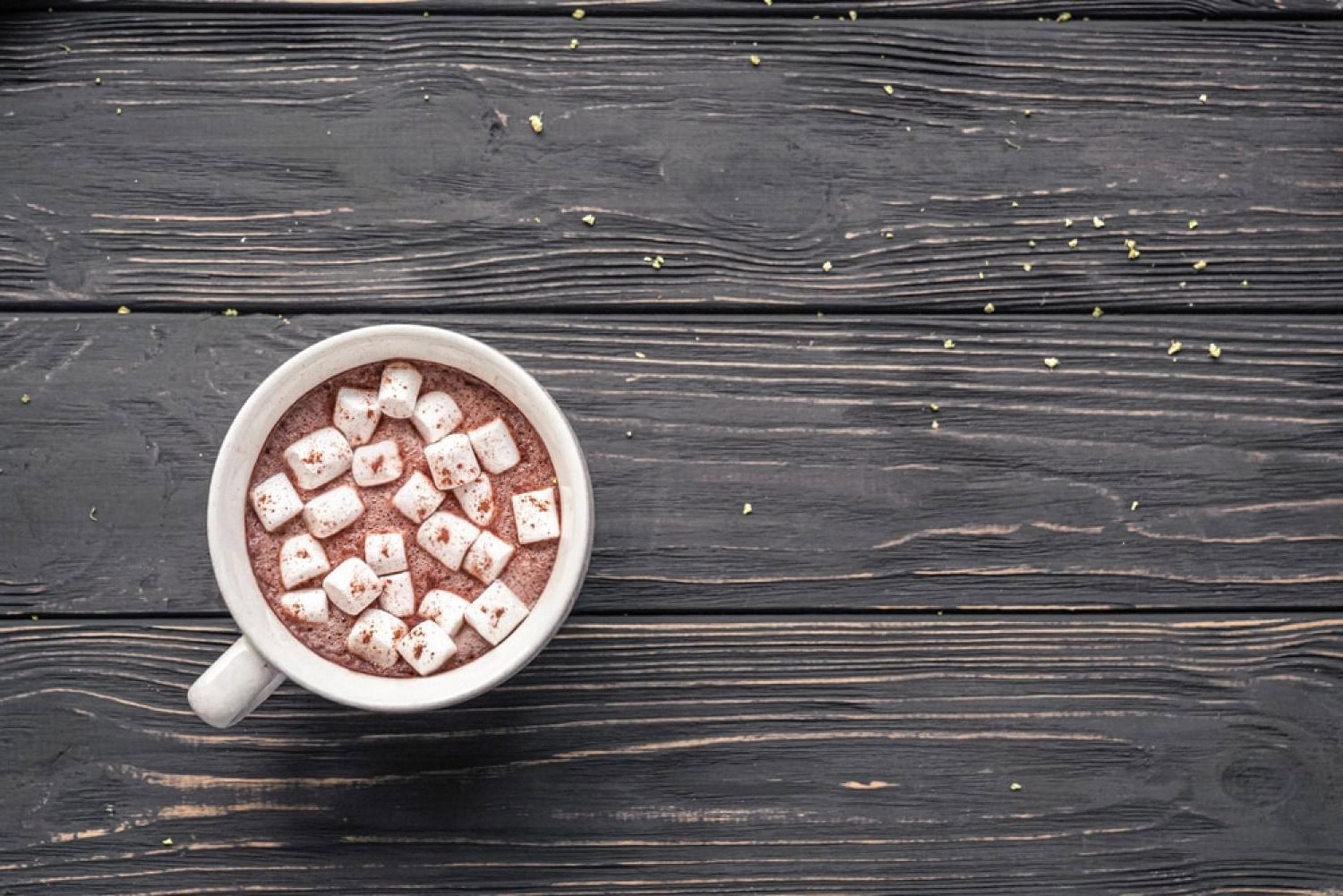Mug of Belgian hot chocolate topped with marshmallows on a dark wooden table